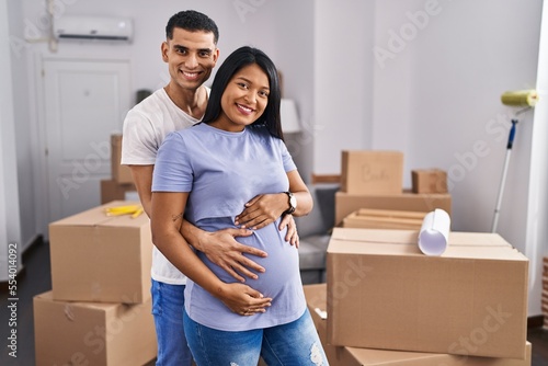 Young latin couple expecting baby hugging each other standing at new home © Krakenimages.com