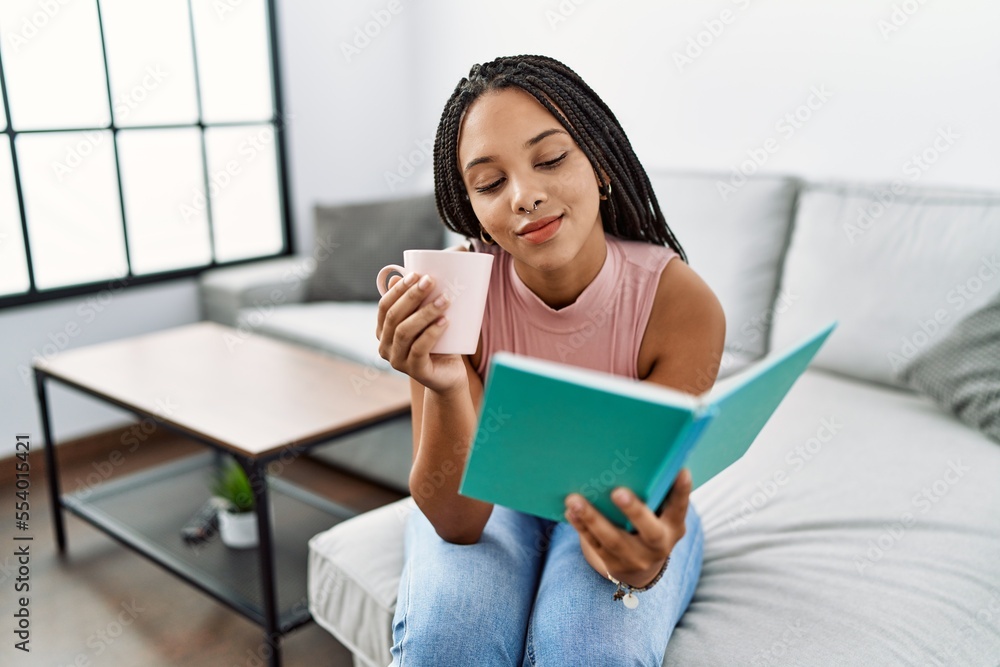 Young african american woman reading book and drinking coffee at home Young african american woman reading book and drinking coffee at home