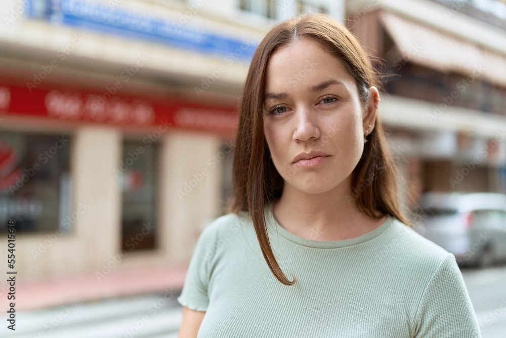 Young beautiful woman standing with serious expression at street