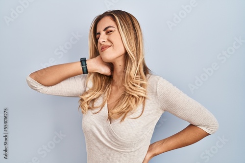 Photos Young blonde woman standing over isolated background suffering of neck ache inju