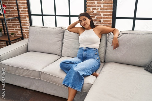 Young hispanic woman smiling confident sitting on sofa at home