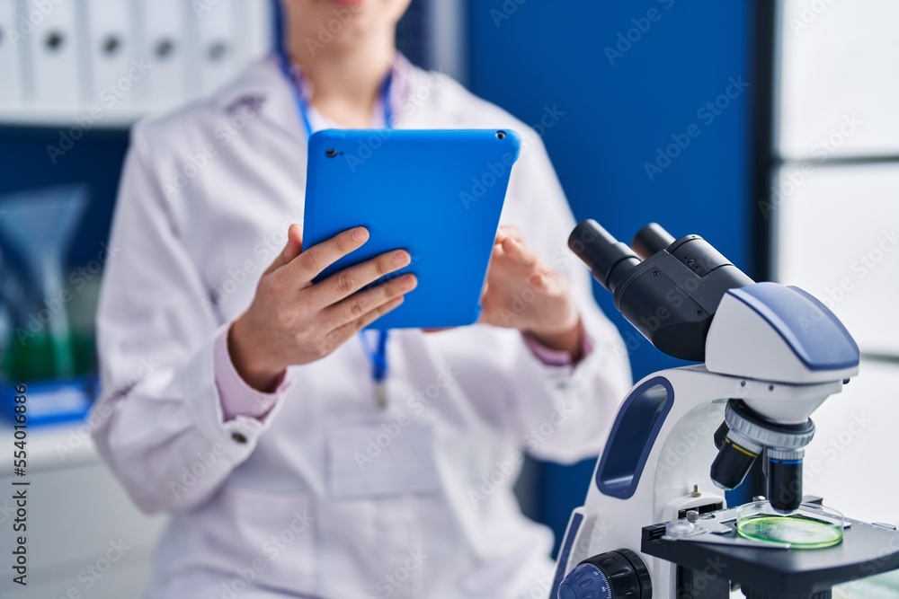 Young hispanic woman scientist using touchpad working at laboratory Young hispanic woman scientist using touchpad working at laboratory