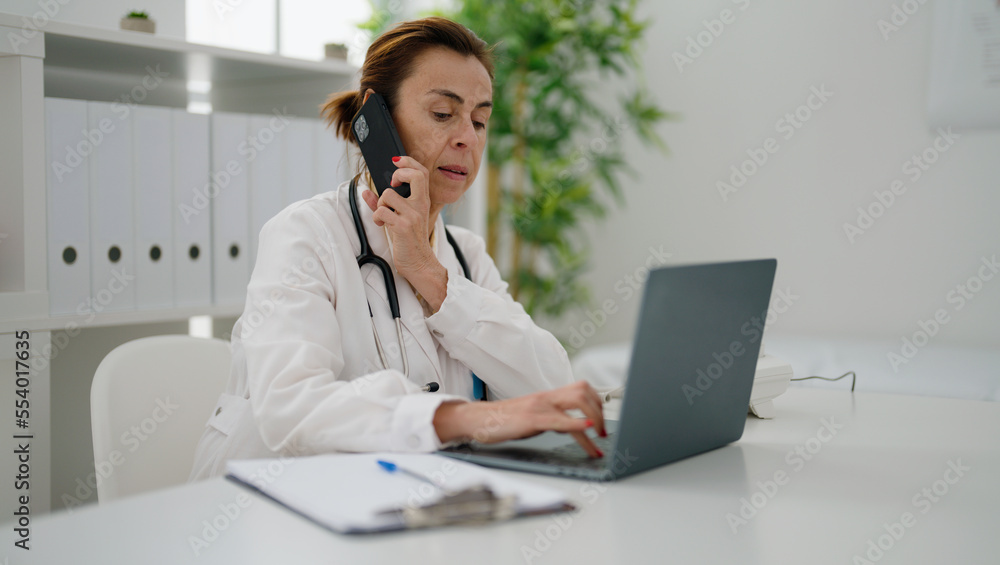 Middle age hispanic woman wearing doctor uniform talking on the smartphone at clinic Middle age hispanic woman wearing doctor uniform talking on the smartphone at clinic