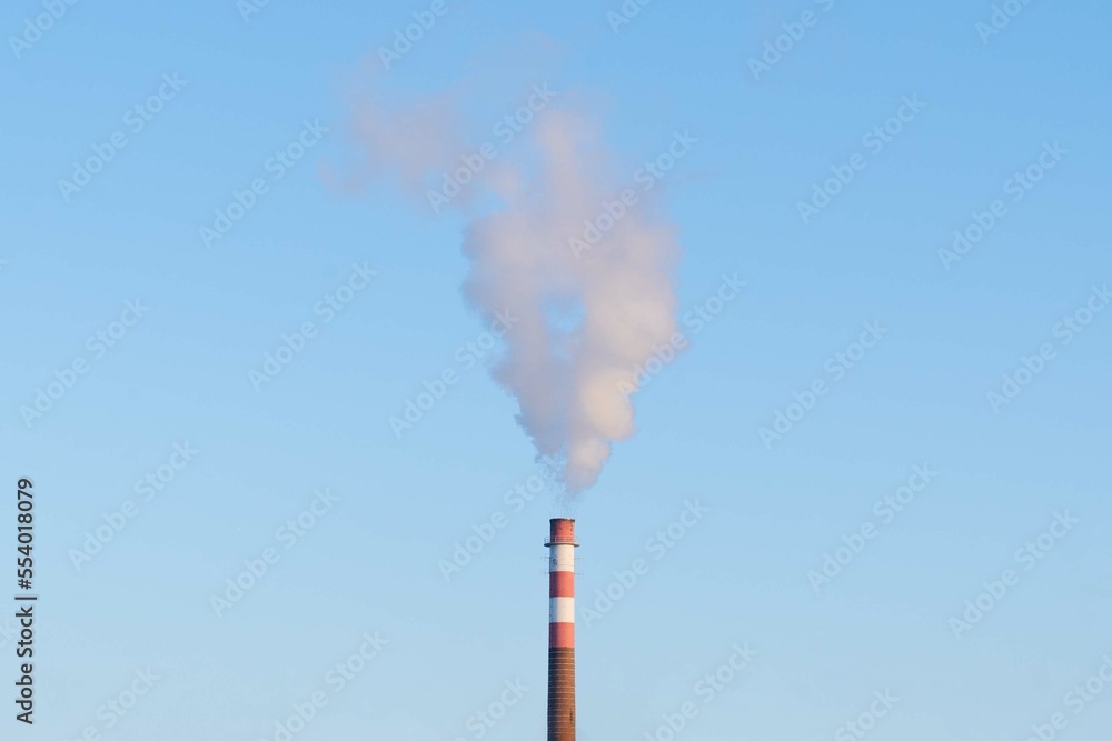 Smoke billowing from a factory chimney under a blue sky