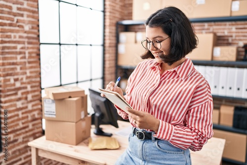 Young woman ecommerce business worker writing on notebook at office