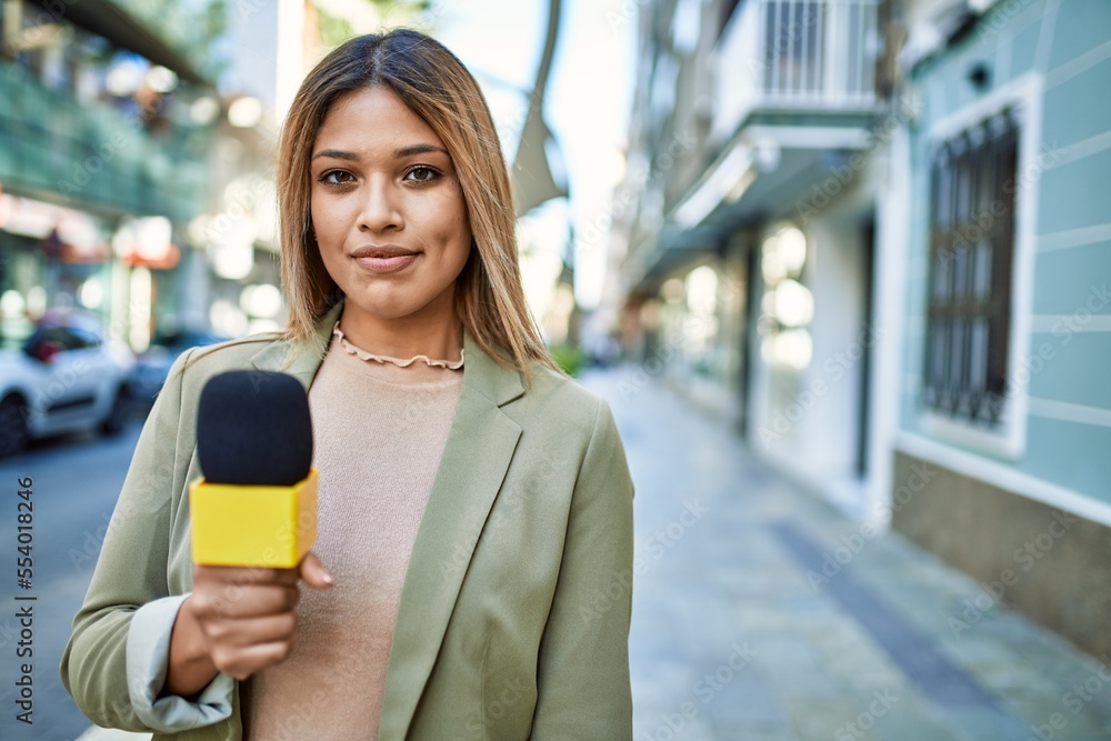 Young latin woman smiling confident using microphone at street Young latin woman smiling confident using microphone at street