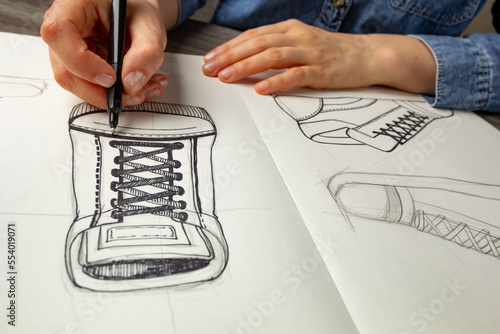 Obraz na płótnie The designer draws sketches of shoes on paper. w salonie