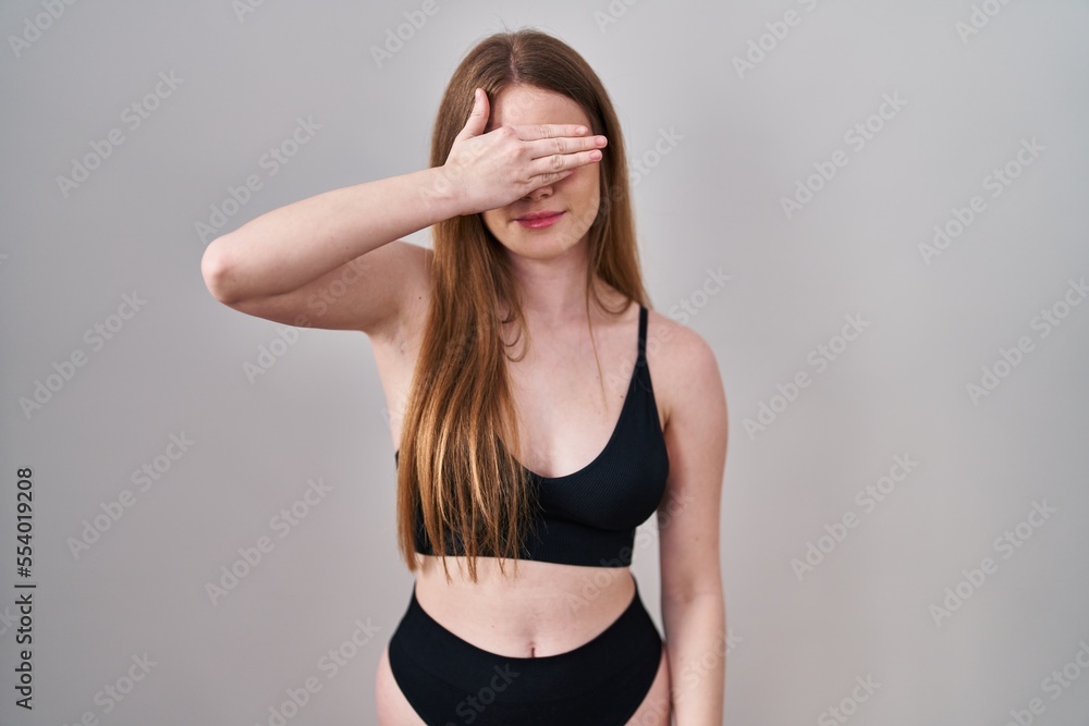 Young caucasian woman wearing lingerie smiling and laughing with hand on face covering eyes for surprise. blind concept. Young caucasian woman wearing lingerie smiling and laughing with hand on face covering eyes for surprise. blind concept.