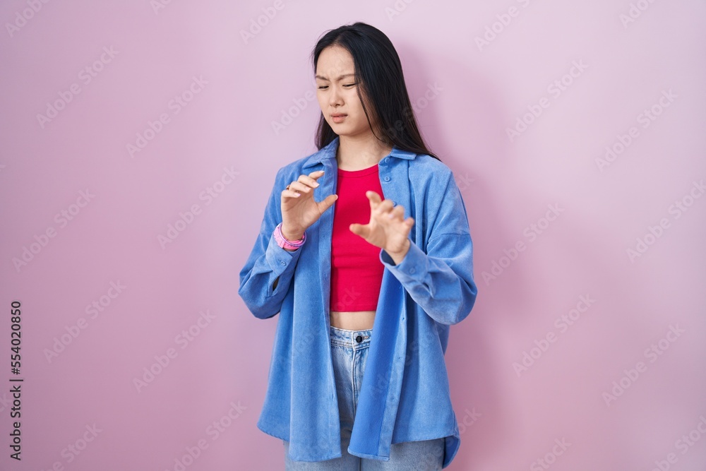 Young asian woman standing over pink background disgusted expression, displeased and fearful doing disgust face because aversion reaction. Young asian woman standing over pink background disgusted expression, displeased and fearful doing disgust face because aversion reaction.