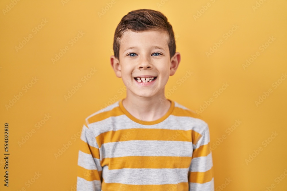 Young caucasian kid standing over yellow background with a happy and cool smile on face. lucky person. Young caucasian kid standing over yellow background with a happy and cool smile on face. lucky person.