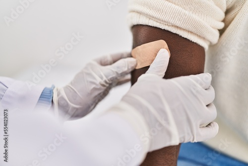 Man and woman doctor and patient putting band aid at clinic