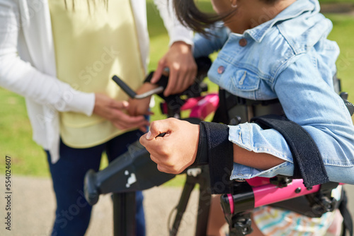 Close up mother helping disabled daughter with arm straps on rollator photo