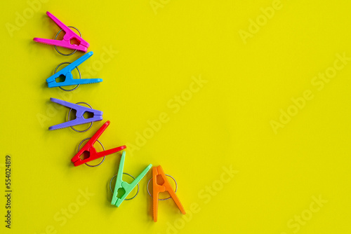 Plastic clothes pin 6 colors, isolated on yellow background. photo