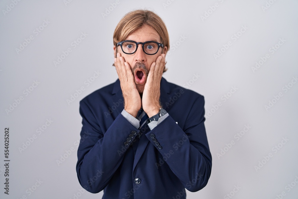Caucasian man with mustache wearing business clothes afraid and shocked, surprise and amazed expression with hands on face Caucasian man with mustache wearing business clothes afraid and shocked, surprise and amazed expression with hands on face