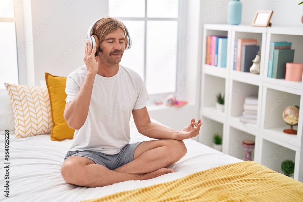 Young blond man doing yoga exercise sitting on bed at bedroom Young blond man doing yoga exercise sitting on bed at bedroom