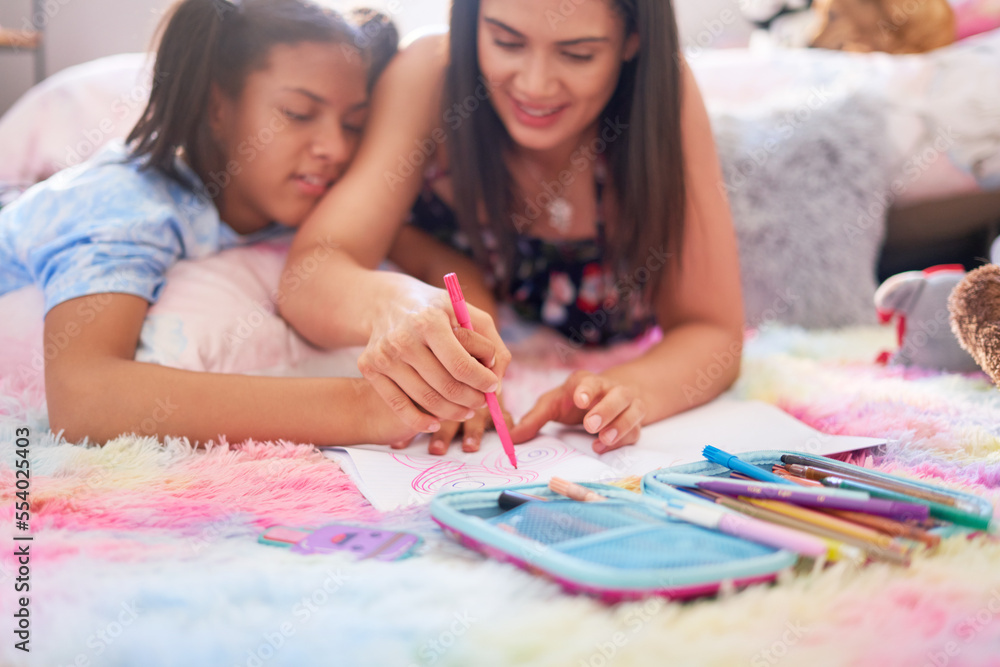 Mother and daughter drawing with marker pen in notebook on rug Mother and daughter drawing with marker pen in notebook on rug