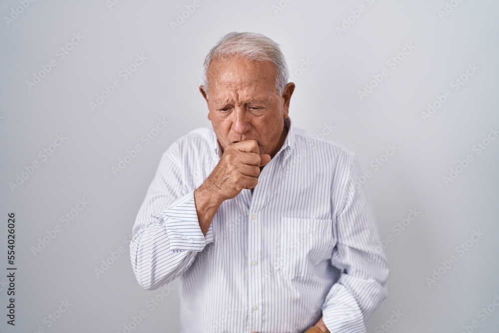 Senior man with grey hair standing over isolated background feeling unwell and coughing as symptom for cold or bronchitis. health care concept. Senior man with grey hair standing over isolated background feeling unwell and coughing as symptom for cold or bronchitis. health care concept.