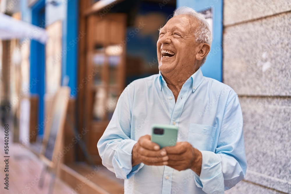 Senior grey-haired man smiling confident using smartphone at street Senior grey-haired man smiling confident using smartphone at street