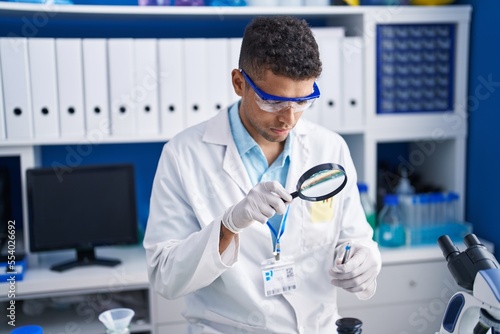 African american man scientist using magnifying glass working at laboratory