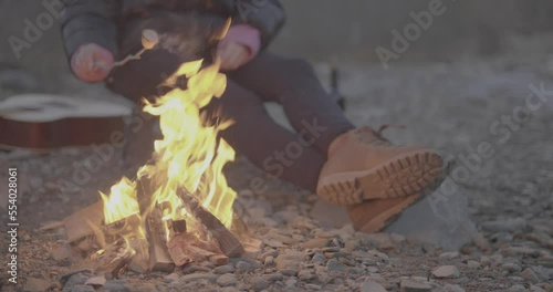 Girl woman roasting a marshmallow on a stick in a camping bone fire flames 4K F-LOG video format