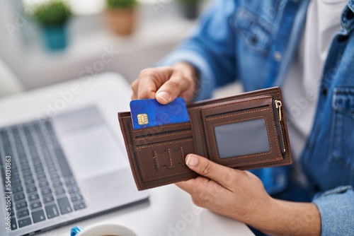 Young arab man using laptop and credit card sitting on table at home