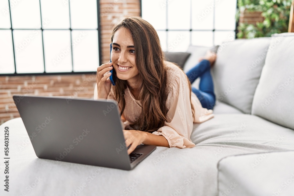 Young hispanic woman smiling confident using laptop and talking on the smartphone at home Young hispanic woman smiling confident using laptop and talking on the smartphone at home