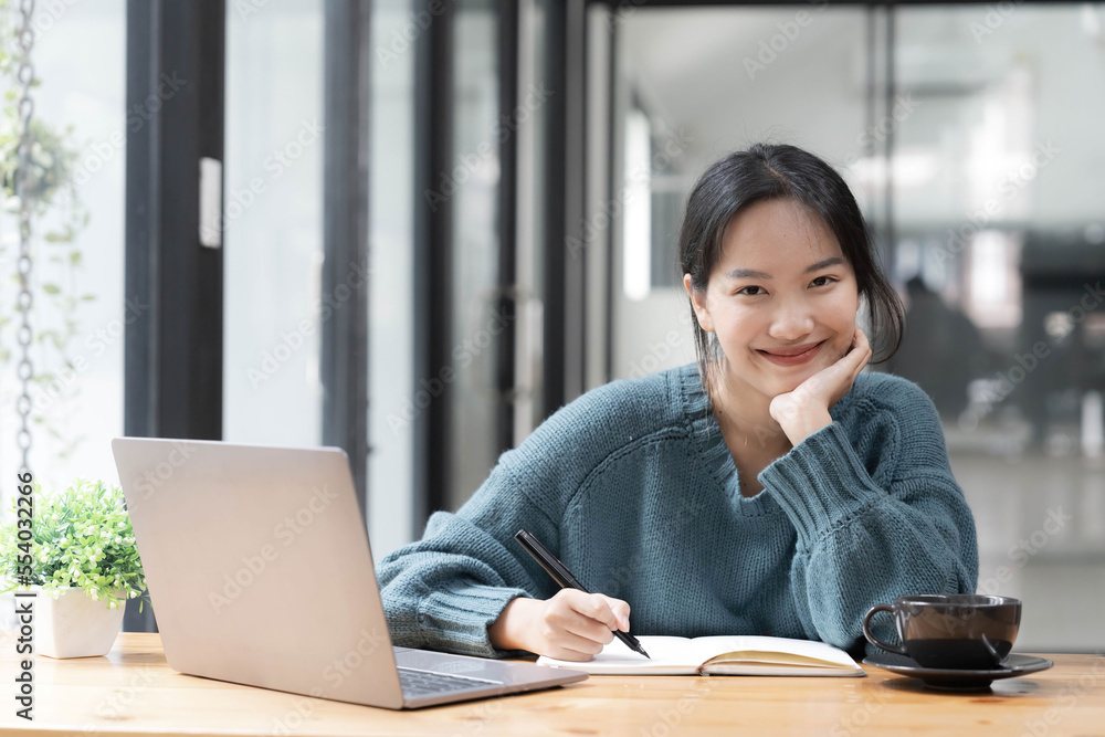 Beautiful women student studying online takes notes on her laptop to gather information about her work smiling face and a happy study posture. Beautiful women student studying online takes notes on her laptop to gather information about her work smiling face and a happy study posture.