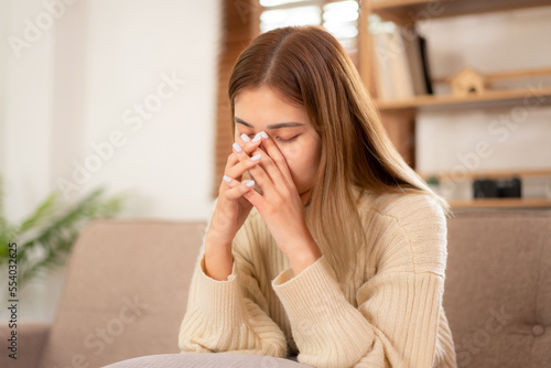 Young asian woman wearing sweater and sitting to covering nose with hands while having a headache and flu