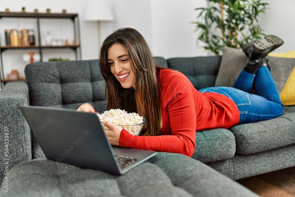 Young woman watching movie lying on sofa at home Young woman watching movie lying on sofa at home