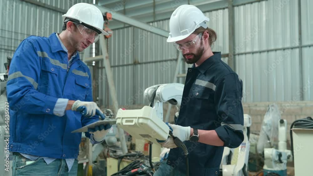 The two engineers check the operation of welding robots. ready to transfer and exchange experiences each other's skills The two engineers check the operation of welding robots. ready to transfer and exchange experiences each other's skills