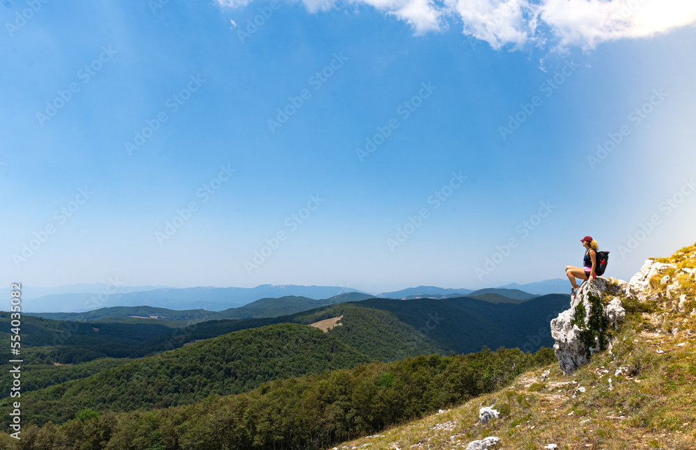 Young female explorer sitting looking at a mountain panorama