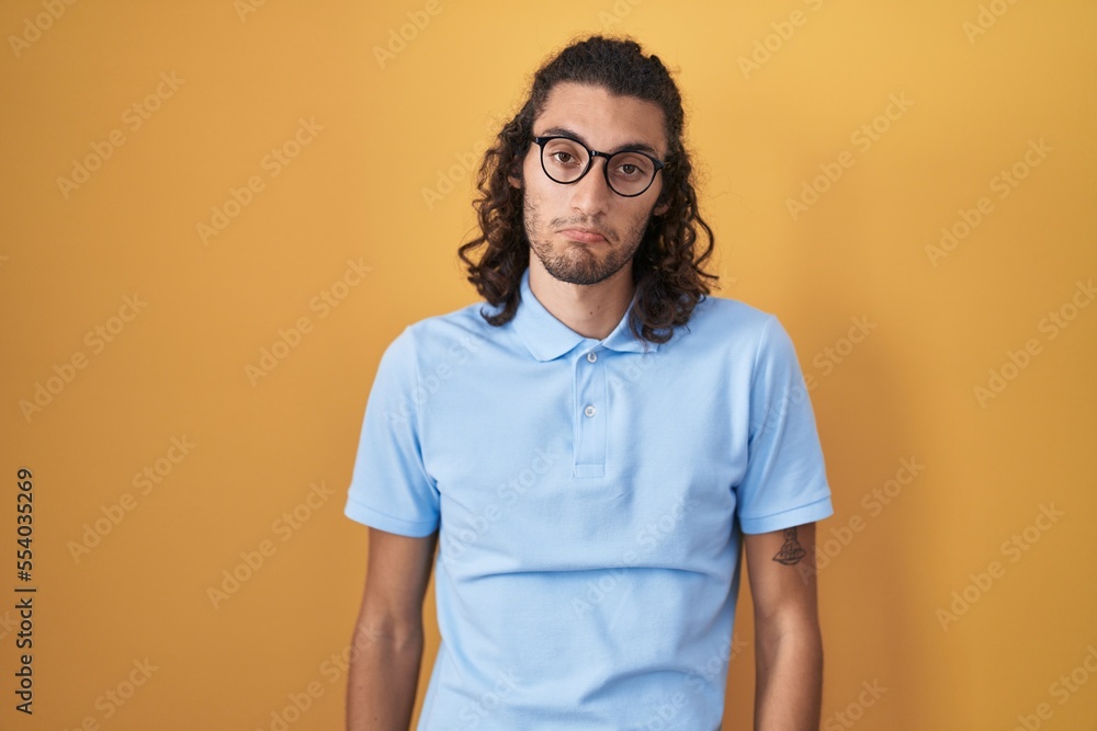 Young hispanic man standing over yellow background depressed and worry for distress, crying angry and afraid. sad expression. Young hispanic man standing over yellow background depressed and worry for distress, crying angry and afraid. sad expression.