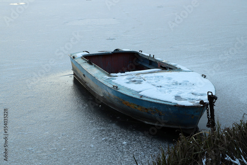 A boat in the ice of a frozen lake in winter 