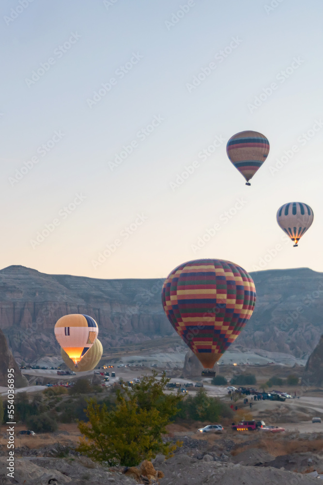 Colorful hot air balloons fly over the fabulous rocks in Cappadocia, Turkey.