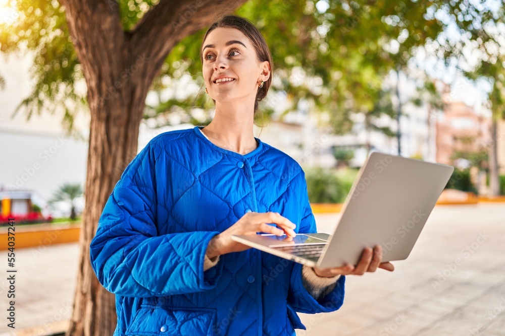 Fototapeta premium Young caucasian woman smiling confident using laptop at park
