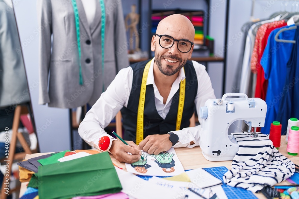 Young bald man tailor smiling confident drawing on notebook at tailor shop Young bald man tailor smiling confident drawing on notebook at tailor shop
