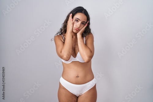 Young hispanic woman wearing white lingerie tired hands covering face, depression and sadness, upset and irritated for problem © Krakenimages.com