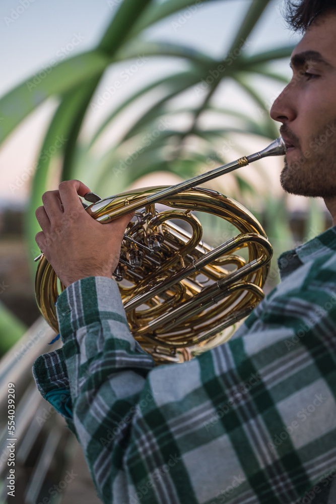 Musician walking on a bridge with his horn in his hand.