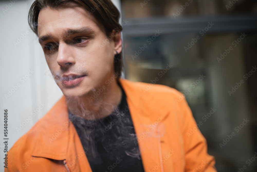Young brunette man in jacket smoking outdoors. Young brunette man in jacket smoking outdoors.