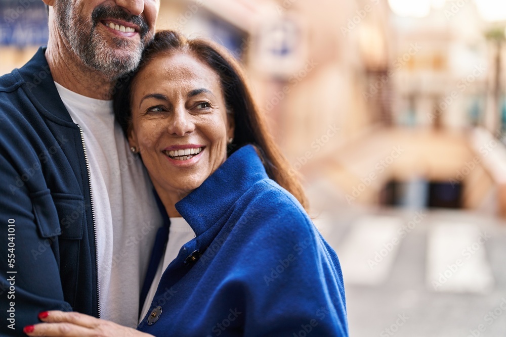 Obraz premium Middle age man and woman couple hugging each other standing at street