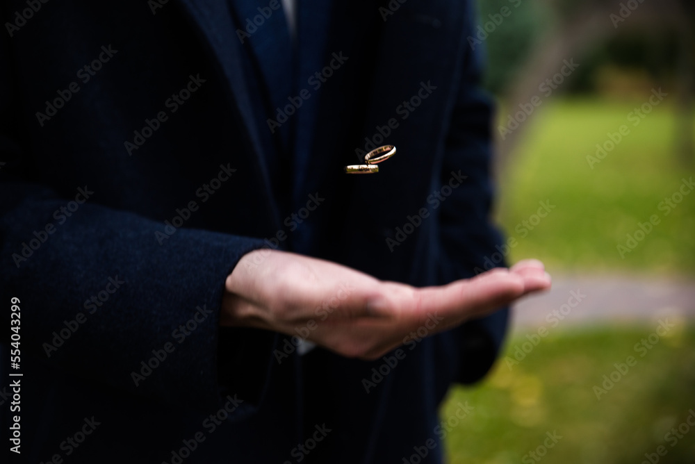 Groom holding wedding rings in hand. Two wedding rings on the floor with contrast wedding rings on floor, on ground, on piano, in hand