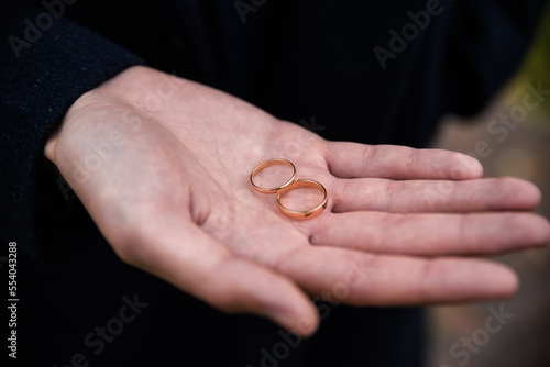Groom holding wedding rings in hand. Two wedding rings on the floor with contrast wedding rings on floor, on ground, on piano, in hand