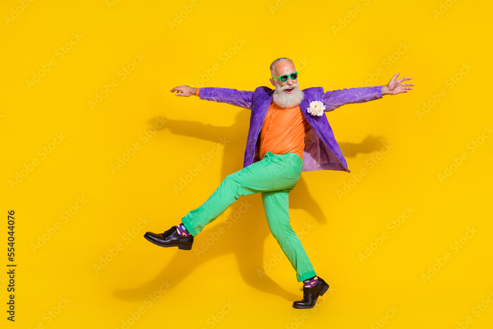 Full length photo of cheerful excited guy dressed violet velvet jacket hands sides walking disco isolated yellow color background