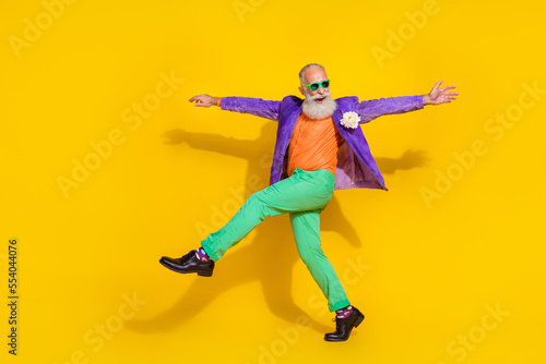 Full length photo of cheerful excited guy dressed violet velvet jacket hands sides walking disco isolated yellow color background © deagreez