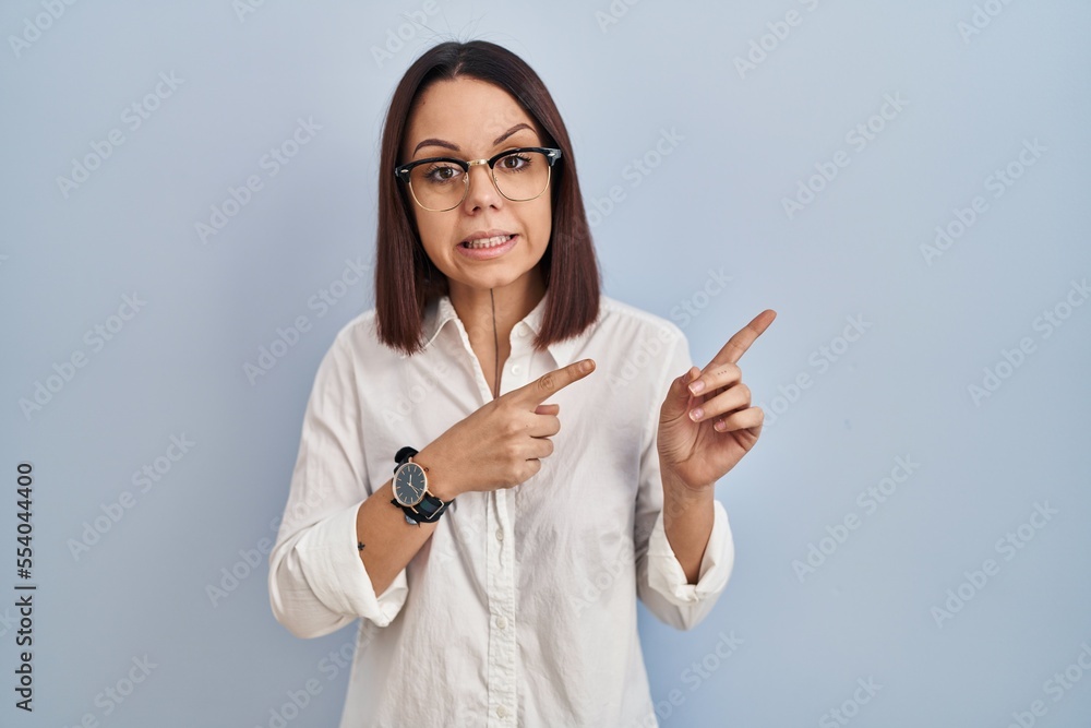 Young hispanic woman standing over white background pointing aside worried and nervous with both hands, concerned and surprised expression Young hispanic woman standing over white background pointing aside worried and nervous with both hands, concerned and surprised expression