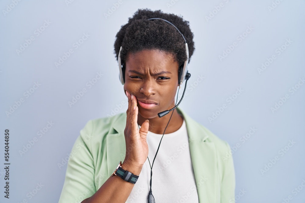 African american woman wearing call center agent headset touching mouth with hand with painful expression because of toothache or dental illness on teeth. dentist concept. African american woman wearing call center agent headset touching mouth with hand with painful expression because of toothache or dental illness on teeth. dentist concept.