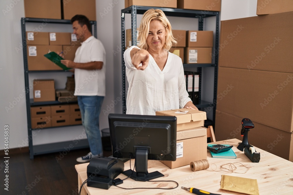 Middle age woman and man working at small business ecommerce pointing with finger to the camera and to you, confident gesture looking serious Middle age woman and man working at small business ecommerce pointing with finger to the camera and to you, confident gesture looking serious
