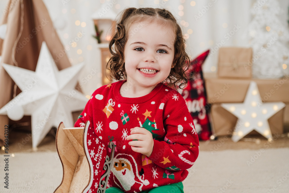 cheerful little girl at home holding presents during christmas time cheerful little girl at home holding presents during christmas time
