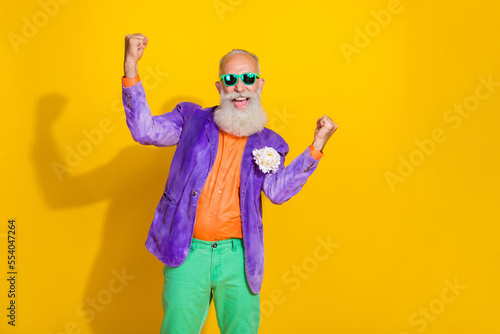 Photo of cheerful eccentric funky man raise hand fist celebrate event champion hooray empty space isolated on yellow color background