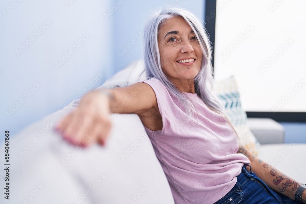 Middle age grey-haired woman smiling confident sitting on sofa at home Middle age grey-haired woman smiling confident sitting on sofa at home